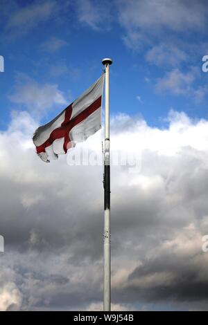 St Georges Fahne in den Wind mit einem bewölkten Himmel im Hintergrund Stockfoto