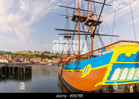 Eine Replik von HMS ENDEAVOUR günstig in Whitby Harbour. Es gibt Hummer Töpfen auf einem Steg im Vordergrund und ein blauer Himmel oben. Stockfoto