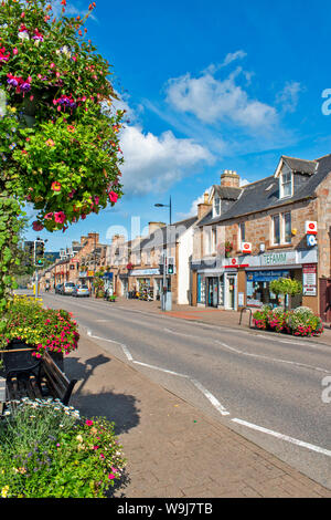 ALNESS ROSS UND CROMARTY SCHOTTLAND DORF STADT IN VOLLER BLÜTE HIGH STREET mit herrlichen zeigt von bunten Blumen in Ampeln Stockfoto