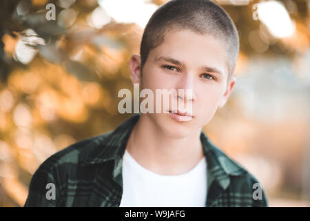 Schöner Mann 17-18 Jahre alt mit kurzer Schnitt über Natur Hintergrund closeup posieren. Herbst Portrait von jugendlich Junge. Mit Blick auf die Kamera. Stockfoto