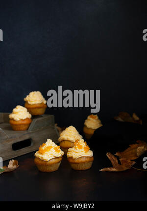 Kürbis Cupcakes auf einem dunklen Hintergrund, Herbst Hintergrund verschiedene Kürbisse und Blätter. Kürbis Süßigkeiten. Halloween und Thanksgiving Süßigkeiten. Vertikale Stockfoto