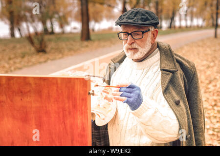 Nahaufnahme von einem älteren Mann Malerei in Park Stockfoto