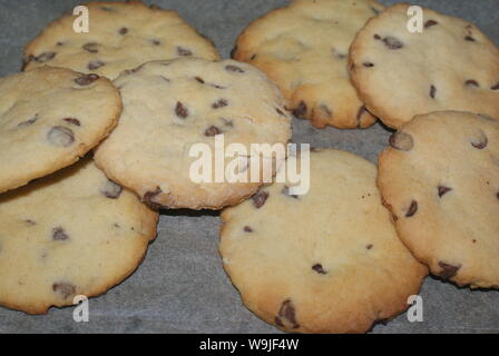 Eine Auswahl an frisch gebackenen Chocolate Chip Cookies auf ein Backpapier. Stockfoto