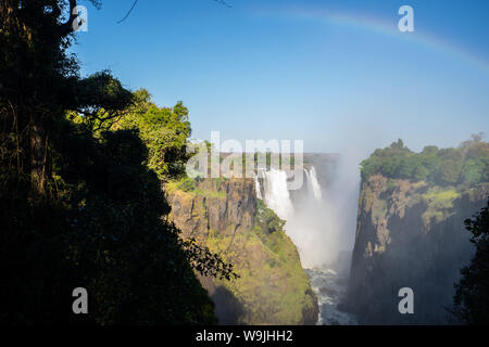 Der Regenbogen im Spray von Victoria Falls auf der Grenze zu Sambia und Simbabwe, Afrika.