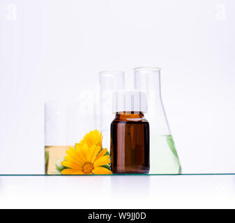 Dunkle kosmetische Flasche aromatisches Öl für pflanzliche Arzneimittel mit Calendula flower auf weißen Hintergrund isoliert. Ringelblumen Extrakt. Stockfoto