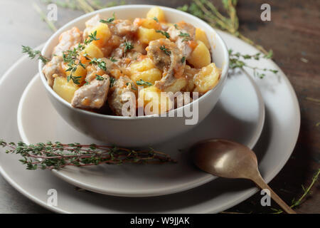 Irish Stew bestreut mit Grün Thymian. Fleisch geschmort mit Kartoffeln, Karotten und Gewürzen auf Holz- Hintergrund. Stockfoto