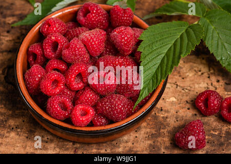 Bündel frische Himbeeren in eine Schüssel auf einen hölzernen Tisch Stockfoto