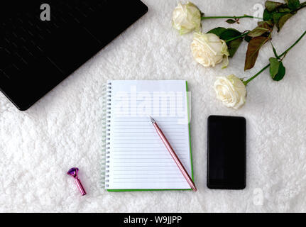 Notepad und schöne Pen auf hellem Hintergrund, weiße Rosen und ein Notebook, geeignet für Hintergrund und Schreiben. Stockfoto