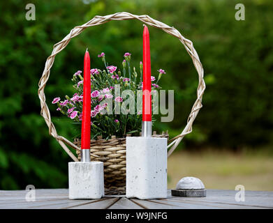 Zwei konkrete candle Sticks mit rosa Blumen auf dem Tisch Stockfoto