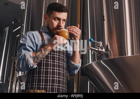 Barkeeper schnuppert Bier im Glas hält er denn das hilft ihm, zu verstehen, wenn er es schon trinken kann. Stockfoto