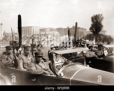 [1930er Jahre Japan - japanische Soldaten in Autos] - Uniformierte japanische Soldaten in Autos halten Ihre gewickelt regimental Fahnen. Der fahnenträger sind von Soldaten Gewehre Holding mit aufgepflanztem Bajonett flankiert. 20. Jahrhundert vintage Silbergelatineabzug. Stockfoto