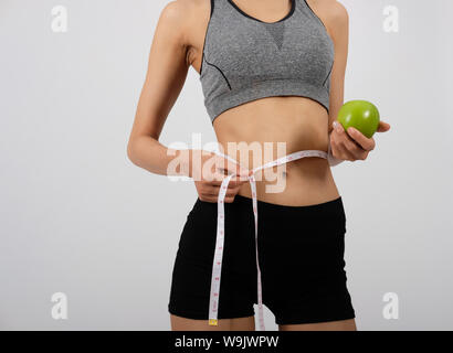 Sportliche fitness Frau in Sportswear mit Messen Taille mit Klebeband auf weißem Hintergrund. ein gesunder Sport Lifestyle Stockfoto