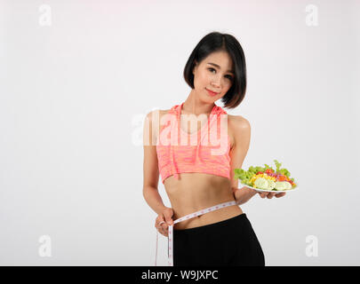 Sportliche fitness Frau in Sportswear mit Salat Schüssel auf weißem Hintergrund. ein gesunder Sport Lifestyle Stockfoto