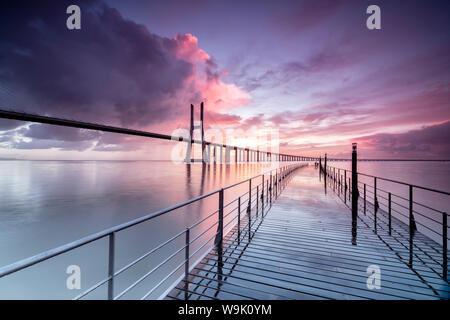 Sunrise Farben der Wolken spiegeln sich in den Fluss Tejo und umrahmen die Vasco da Gama-Brücke in Lissabon, Portugal, Europa Stockfoto