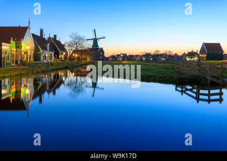 Blaue Leuchten in der Dämmerung auf Holzhäuser und Windmühlen des typischen Dorfes Zaanse Schans, Nord Holland, Niederlande, Europa Stockfoto