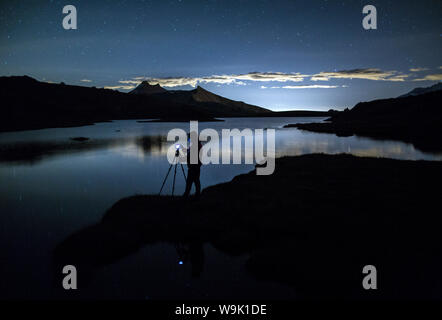 Fotograf bewundert Reflexion über Rossett See in der Nacht, Nationalpark Gran Paradiso, Alpi Graie (Graian Alpen), Italien, Europa Stockfoto