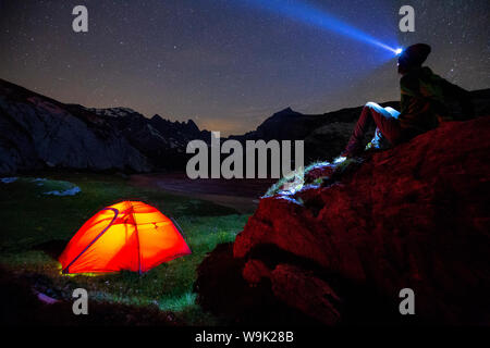 Eine Person sieht bei Stars in der Nähe von seinem roten Zelt, unteren Segnesboden, Flims, Bezirk Imboden des Kantons Graubünden (Graubünden), Schweiz, Europa Stockfoto