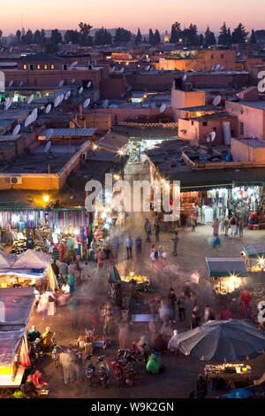 Massen von Einheimischen und Touristen zu Fuß zu den Geschäften und Ständen in der Djemaa el Fna bei Sonnenuntergang, Marrakesch, Marokko, Nordafrika, Afrika Stockfoto