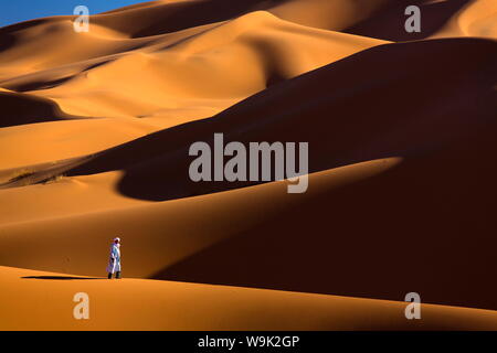 Berber Mann unter den orangefarbenen Sanddünen des Erg Chebbi Sand Meer, Wüste Sahara in der Nähe von Fes, Marokko, Nordafrika, Afrika Stockfoto