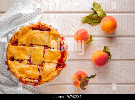 Hausgemachte uns südlichen Peach pie auf weißem Holz- Oberfläche mit raw Pfirsiche Stockfoto