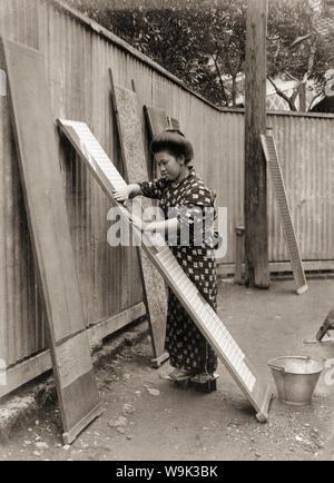 [1910s Japan - Japanische Frau die Wäsche machen] - eine Frau im Kimono und traditionellen headwear ist die Wäsche durch die Verbreitung einer getrennt Kimono auf einem Holzbrett. Vom 1919 (taisho 8). 20. Jahrhundert vintage Silbergelatineabzug. Stockfoto