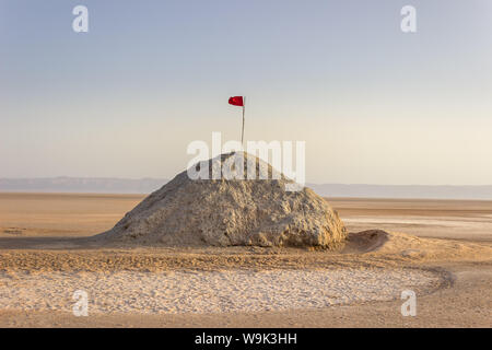 Chott el Djerid, dem größten Salzsee der Sahara in Tunesien und tunesische rote Flagge auf dem Hügel unter dem blauen Himmel Stockfoto