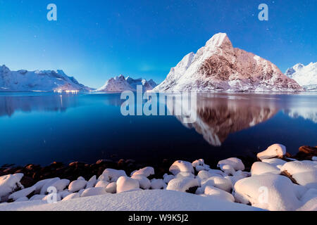 Die schneebedeckten Gipfel sind in das gefrorene Meer auf einer sternenklaren Winternacht wider, Reine Bay, Nordland, Lofoten, Arktis, Norwegen, Skandinavien, Europa Stockfoto