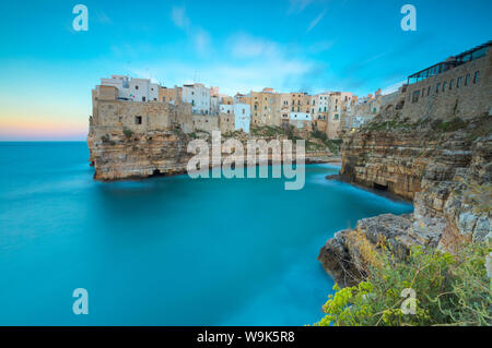 Das türkisfarbene Meer bei Sonnenuntergang durch die Altstadt auf den Felsen thront gerahmt, Polignano a Mare, in der Provinz Bari, Apulien, Italien, Europa Stockfoto