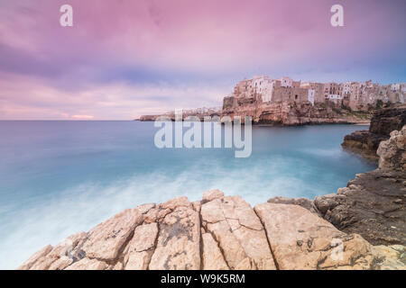 Rosa Sonnenaufgang auf dem türkisblauen Meer durch die Altstadt auf den Felsen thront gerahmt, Polignano a Mare, in der Provinz Bari, Apulien, Italien, Europa Stockfoto