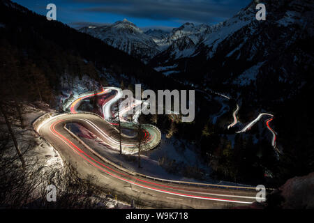 Auto leuchten auf der kurvigen Malojapass Straße bei Nacht, Malojapass, Engadin, Graubünden, Schweiz, Europa Stockfoto