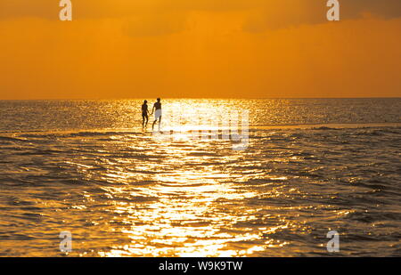 Silhouette von Paar zu Fuß auf einer Sandbank bei Sonnenuntergang, Malediven, Indischer Ozean, Asien Stockfoto