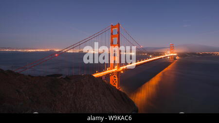 Golden Gate Bridge bei Sonnenuntergang mit der San Francisco Skyline hinter, von Marin Headlands, San Francisco, Kalifornien, USA gesehen glühende