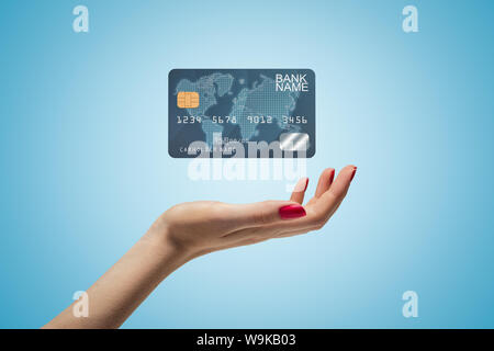 Seite Nahaufnahme von der Frau die Hand nach oben und schwebenden Kunststoff Bank Card von blauen Farbverlauf Hintergrund. Stockfoto