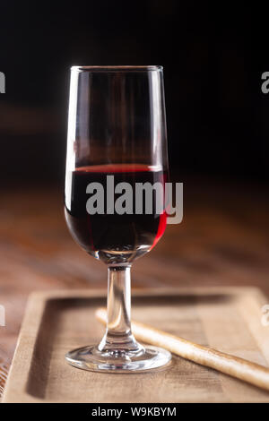 Glas Portwein auf Holztisch und über dunklen Hintergrund Stockfoto