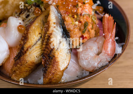 Typische japanische Fisch donburi, Shrimp Tempura, rohe Garnelen, Lachs Filets, gegrillter Thunfisch, Kaviar, Thunfisch Tartar, in Scheiben geschnittene Gurken, raw Wolfsbarsch Fischfilets Stockfoto