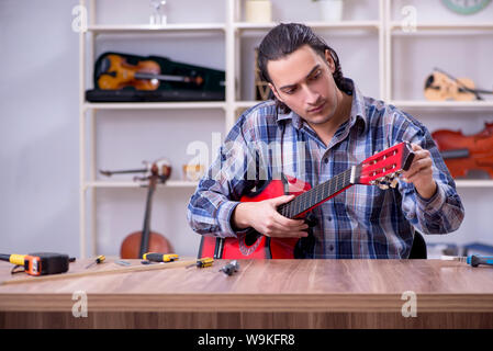 Die junge schöne Handwerker Reparatur Gitarre Stockfoto