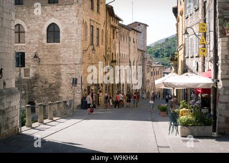 Gubbio, Italien - 11 August, 2019: Touristen besuchen eine Straße in der umbrischen Stadt an einem heißen Sommertag Stockfoto