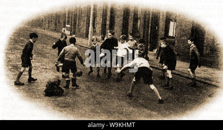 Circa 1940 - Britische Schule Kinder aus dem Norden Englands spielen Fußball auf der Straße Stockfoto