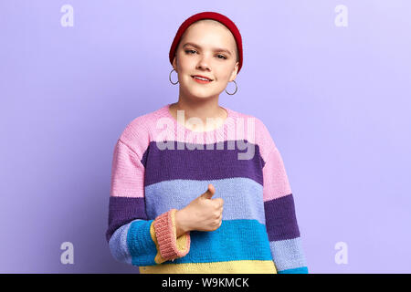 Schöne junge Frau in Mode winter Pullover dabei positive Geste mit der Hand, Daumen hoch und lächelnd über isolierte blauen Hintergrund glücklich. Glück Stockfoto