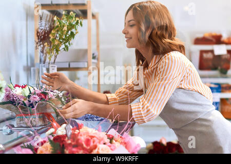 Junge angenehme Florist genießen Sie die Schönheit Ihrer Blumen, Freude, Glück, positive Stimmung. Nahaufnahme Seite Foto anzeigen Stockfoto