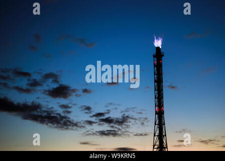 Industrielle flare für die Verbrennung von Erdgas vor dem Hintergrund eines dunklen Abendhimmel Stockfoto