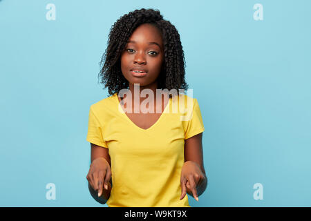 Schöne Mädchen mit lockigem Haar zeigt mit Index Finger, suchen dort. Isolierte blauen Hintergrund. studio Shot Stockfoto