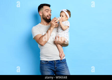 Gerne pflege Vati an adorable Baby trinken Milch aus der Flasche. nach oben schließen Foto. Liebe, Familie, Beziehung Konzept. studio Shot Stockfoto