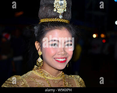Kostümierte Thai Girl trägt eine goldene Lanna-stil Spitzenkleid und aufwendige Frisur mit Haar Schmuck und Ohrringe während eines ländlichen Yi Peng Parade. Stockfoto