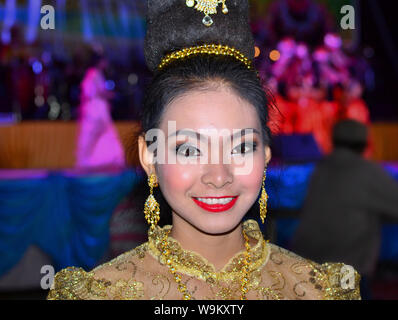 Kostümierte Thai Girl trägt eine goldene Lanna-stil Spitzenkleid und aufwendige Frisur mit Haar Schmuck und Ohrringe während eines ländlichen Yi Peng Parade. Stockfoto