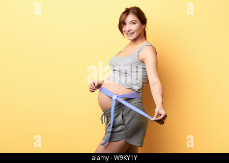 Lächelnd bezauberndes Mädchen ihre großen Bauch, Frau ist bereit, tio Geburt geben. Isolierte gelben Hintergrund, studio Shot, oreparation für Geburt Stockfoto