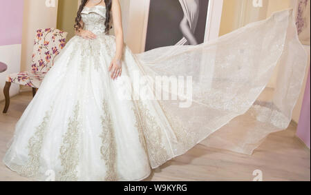 Die perfekte Hochzeit Kleid mit einem vollen Rock auf einem Kleiderbügel im Zimmer der Braut. Braut im weißen Kleid. Die Braut ist Spinnen im Zimmer. Braut an Stockfoto