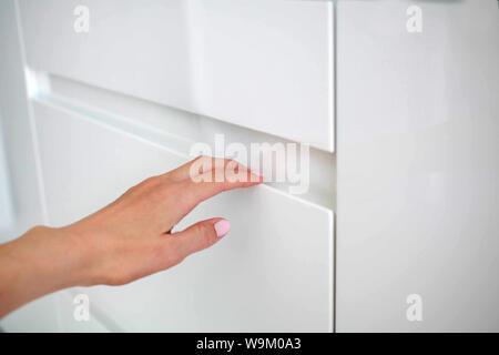Frau Hand öffnet sich moderne Tür weiße Küche mit den versteckten Griff Stockfoto