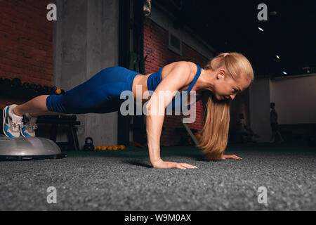 Schlanke Athlet Übungen im Sport Center, de lossing" gewichten. volle Länge Seitenansicht Foto. Fitness, Kreuz anbringen Stockfoto