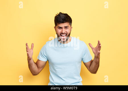 Junge emotionale gutaussehenden Mann im weißen T-Shirt schreien und schreien mit aggressiven Ausdruck und die Arme angehoben. Frustration Konzept. Ich kill dich. ne Stockfoto